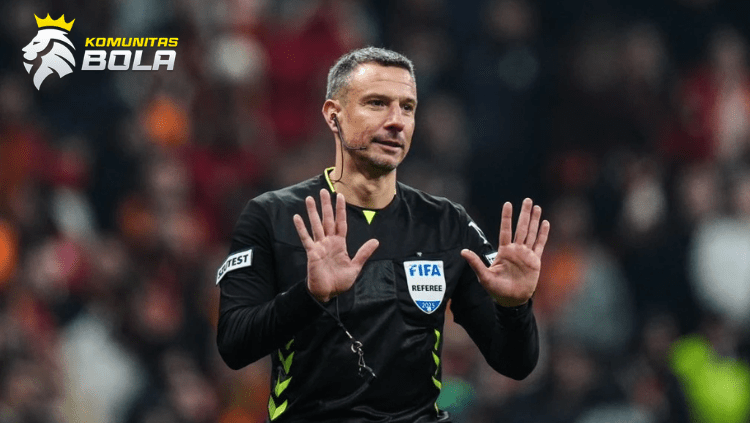 Wasit FIFA mengenakan seragam hitam memberikan isyarat dengan kedua tangan saat memimpin pertandingan sepak bola internasional di stadion.